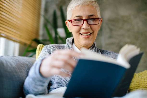 istock Mature woman resting on sofa and reading book 904912486
