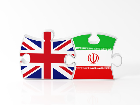 Jigsaw puzzle pieces textured with United Kingdom and Iranian flags on white. Horizontal composition with copy space. Clipping path is included.