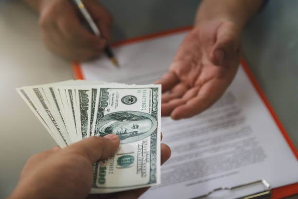 Man offering batch of hundred dollar bills. Close up of business man signing contract making a deal, business contract details. stock photo