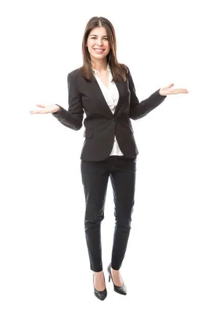 Full length portrait of a beautiful young woman in a suit working as a hostess and greeting people with a smile