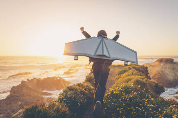 Business Boy with Jet Pack in California A young boy dressed in business suit and tie wears a homemade jetpack and flying goggles raises his arms in the afternoon sun while running to take off into the air on an outcropping above the surf in Montana de Oro State Park, California. This young entrepreneur is ready to take his new business to new heights. confident boy stock pictures, royalty-free photos & images