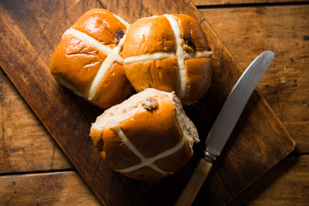 istock three hot cross buns on an aged wood board. 904944892