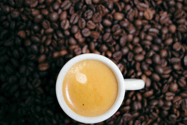 istock Espresso creamy coffee on a white cup over many brown roasted coffee beans 904951356