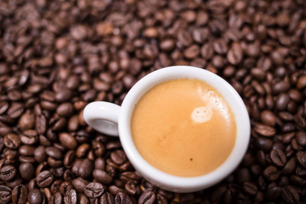 istock Espresso creamy coffee on a white cup over many brown roasted coffee beans 904951402