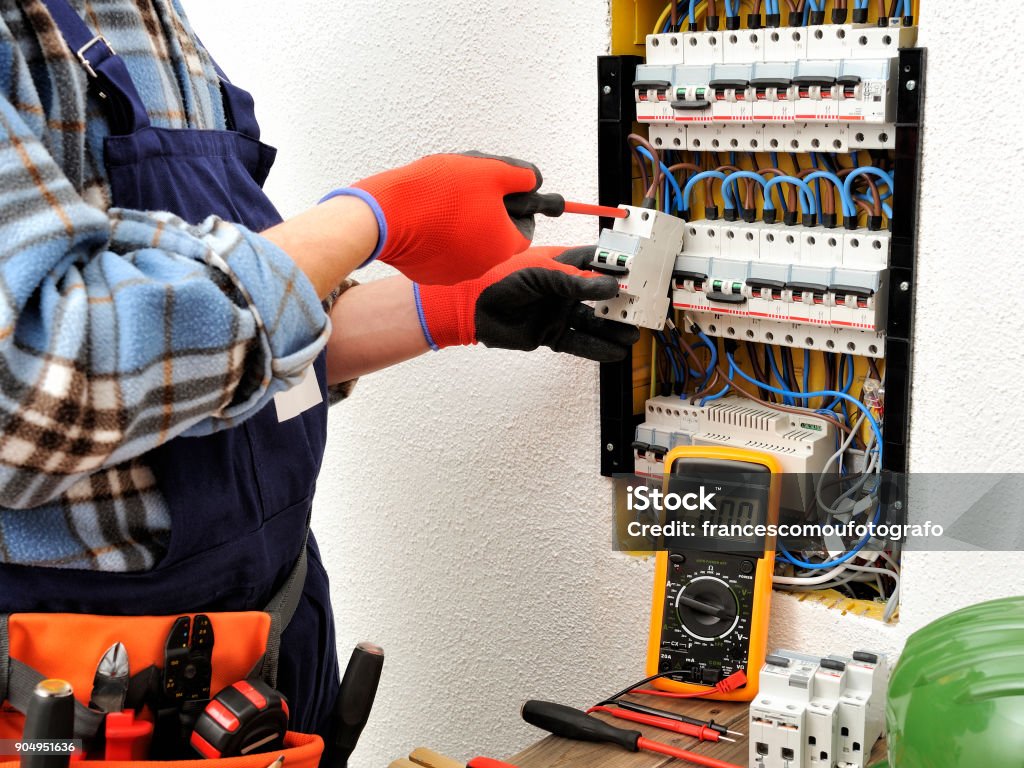 Young electrician technician at work on a electrical panel with protective gloves Young electrician technician fixes the electric cable to the magnetothermic switch with the screwdriver 20-29 Years Stock Photo