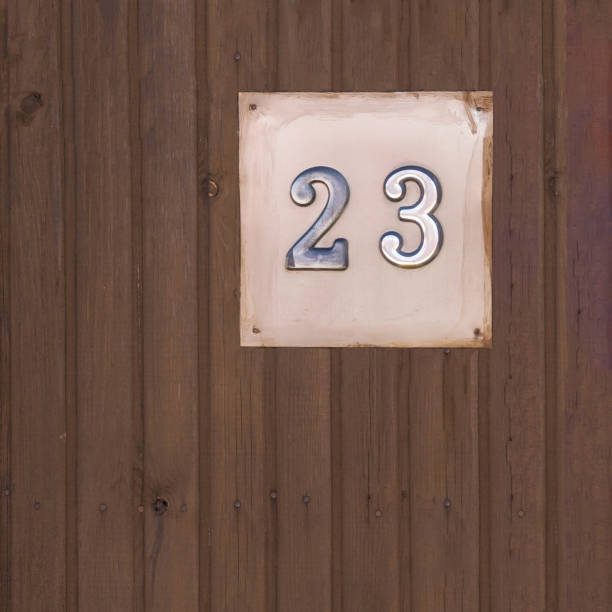 istock Old door number twenty three (23) on a wooden background. 904965722