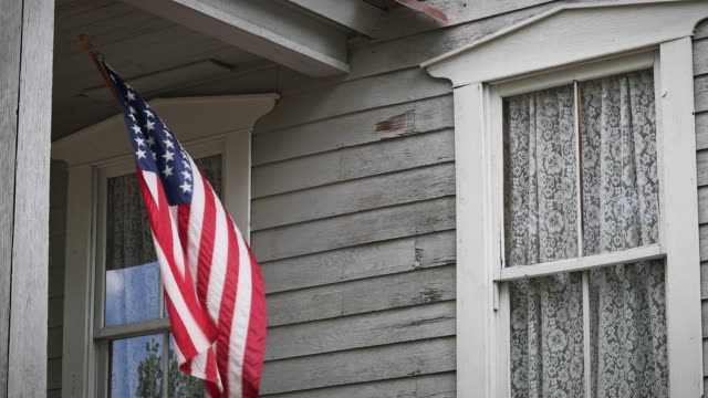 An American Flag Waves on A Farmhouse Porch