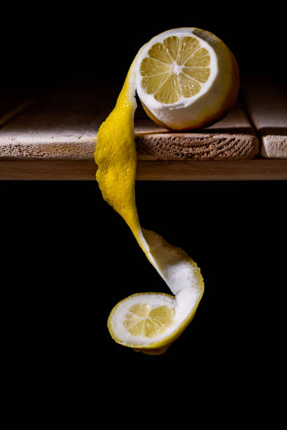 lemon cut and peeled, with skin coiled on wooden table stock photo