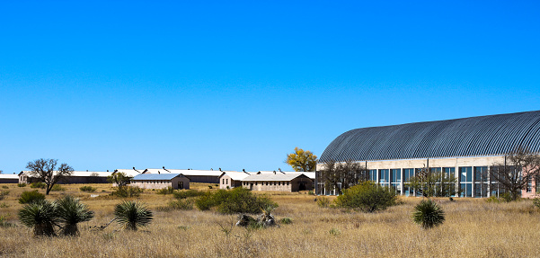 old military base with airplane hangar on the right of the photo in the desert of west texas with a bright blue sky in the background and multiple barracks building exteriors throughout