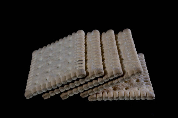 Crumbly biscuits tied with a string on a glass table. Tasty cakes on a mirror table, black background