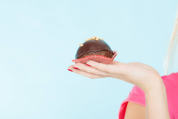istock Woman hand holding chocolate cupcake about to bite 905010612
