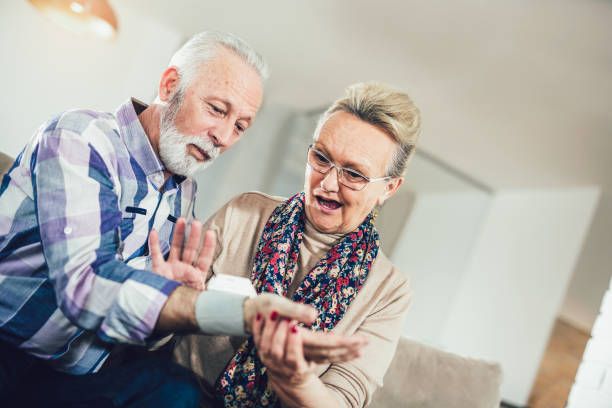 feliz pareja senior tomando la presión arterial en la sala de estar - blood pressure gauge surveillance home interior house fotografías e imágenes de stock