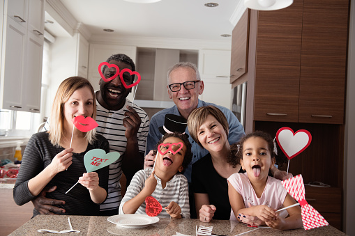 Mixed race family Father mother little daughter and son grandmother and grandfather doing photobooth during Valentine's day. Photos was taken in Quebec Canada. This photo can be use also for mother's day, father's day or birthday. Can also use for modern family brief 679006863