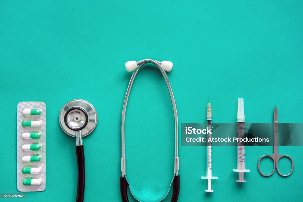 Medical equipments on green background Medical equipments including stethoscope, scissors, syringes and capsules on green background, top view Healthcare And Medicine Stock Photo