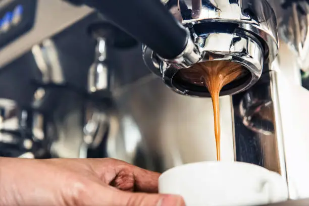 Photo of Coffee dripping from the machine into the cup