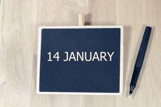 istock sentence JAN 14 written with chalkboard on a wooden table with pen. 905034834