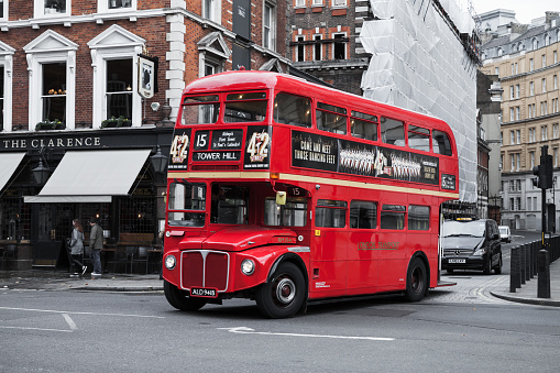 London, United Kingdom - October 21, 2017: Red double-decker bus goes on the street, one of the most popular symbols of the city. Ordinary people walk sidewalks