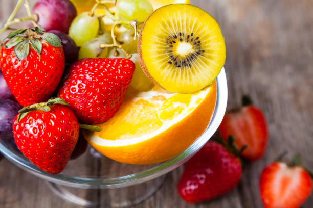 Ripe fruits on a transparent plate on a wooden background. Healthy eating.