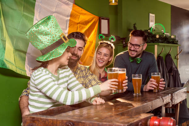 istock Four good friend talking and drinking beer in pub with Irish flag on background and smile 905090796