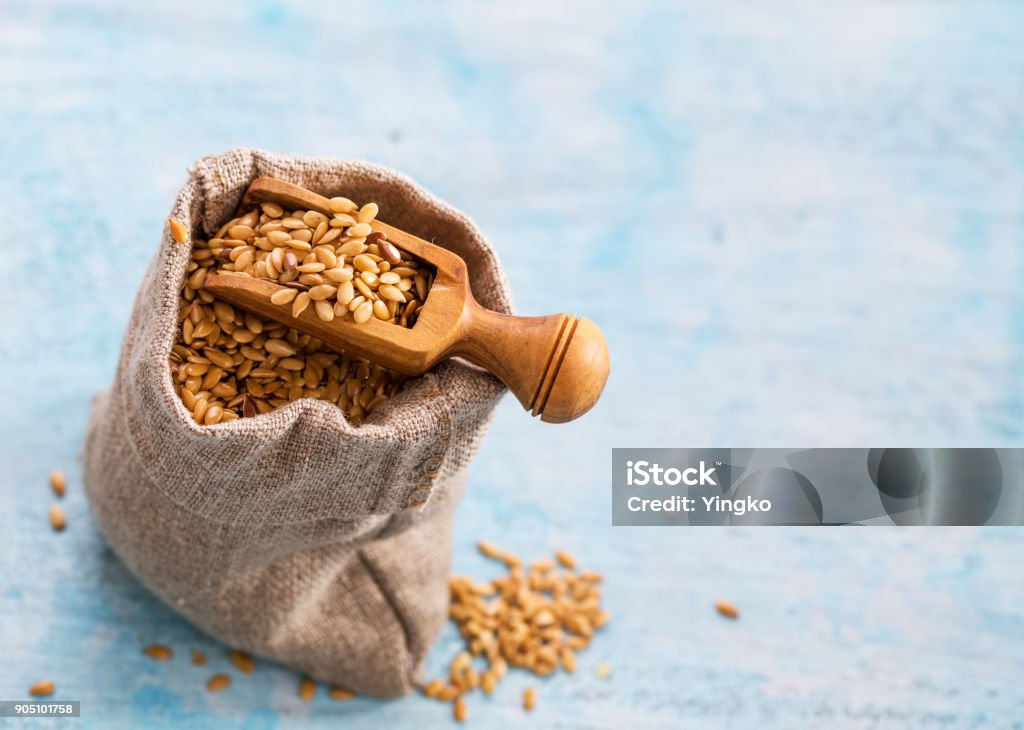 Flax seeds in bag and scoop Golden flax seeds in bag and scoop closeup on light blue background with copy space Flax Seed Stock Photo