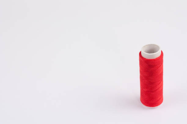 istock One red bobbin of new colorful thread on white background 905102352