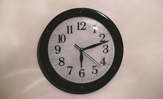 Closeup view of an old retro clock on white wall.