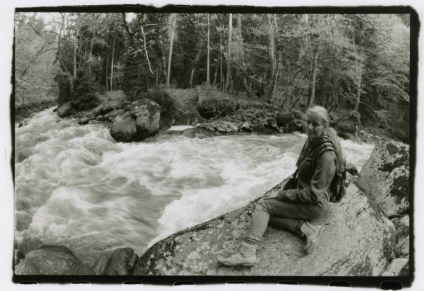 istock A girl with a backpack on her back sits on the river bank. 905107242