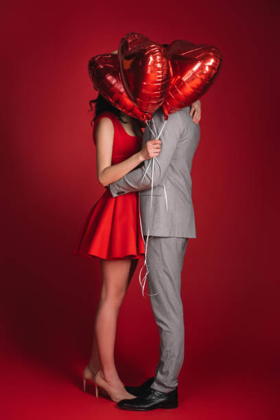 istock couple covering faces with bundle of balloons on red 905107468