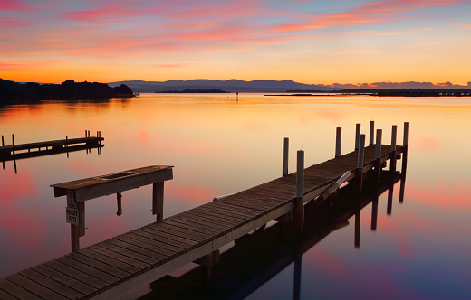 Rustic old timber jetty with old basin on calm waters at sunrise