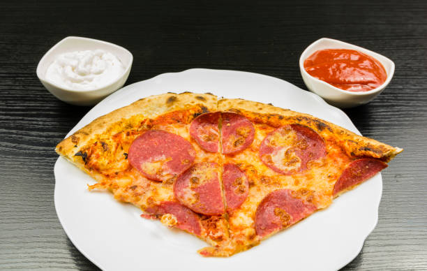 istock A portion of pizza on a plate and sauces in bowls. 905110156
