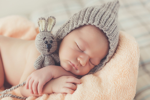 Feliz sonriente niño bebé hicieron punto el sombrero durmiendo profundamente en la cesta photo