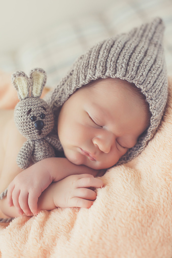 Feliz sonriente niño bebé hicieron punto el sombrero durmiendo profundamente en la cesta photo