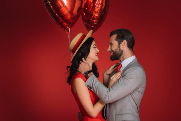 istock stylish couple with red balloons looking at each other 905122344