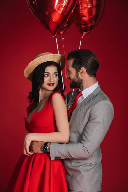 istock stylish couple with red balloons hugging isolated on red 905122498
