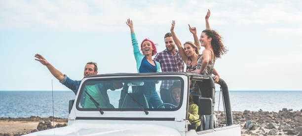 amigos turistas felices haciendo la excursión en el desierto en automóvil jeep convertible - jóvenes que se divierten viajando juntos - amistad, concepto de estilo de vida y vacaciones de juventud - centran en chicos con las manos arriba - 4x4 fotografías e imágenes de stock