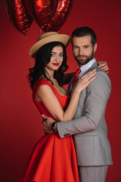 istock stylish couple with red balloons looking at camera 905125312