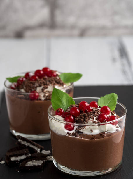 istock Chocolate mousse with currant and mint in a glasses on a black stone background. 905125428