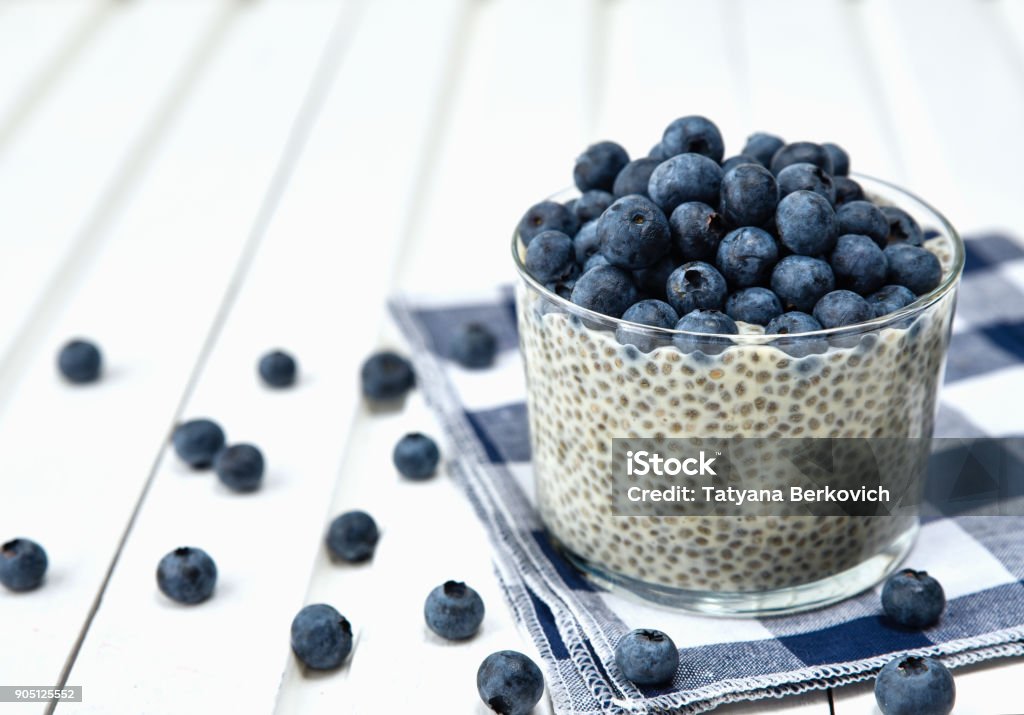 Chia pudding with blueberries on striped canvas, white wood background Chia seed Stock Photo