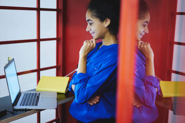 le sourire d’afro américain hipster fille regarder drôle la vidéo sur les commandes de sites internet en coworking space au dispositif portable moderne, connexion à internet sans fil. bonne humeur jeune femme avoir une conversation vidéo - lundi noir chinois photos et images de collection