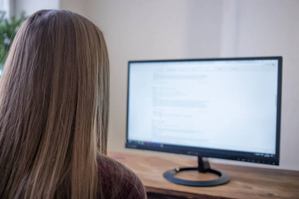 istock A student working at home using the computer, watching the screen. Close-up rear view over the shoulder. 905127290