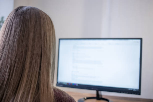 istock A student working at home using the computer, watching the screen. Close-up rear view over the shoulder. 905127360