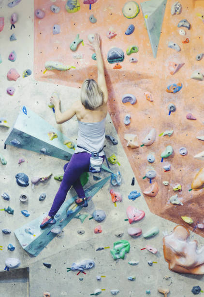istock Young woman practicing rock-climbing on a rock wall indoors 905130998