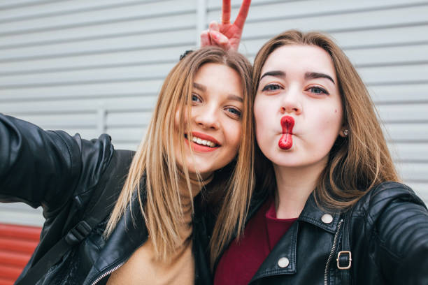 Two young girls taking selfie using smartphone Two young girls taking selfie using smartphone in city lipstick photos stock pictures, royalty-free photos & images