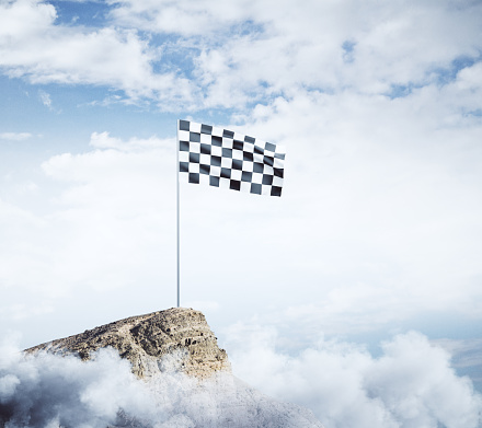 Checkered flag on mountain top. Cloudy sky background. Win concept