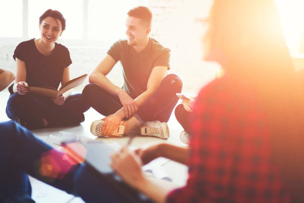 istock Cheerful young hipster guys laughing during educational training sitting in office interior.Positive two male and female students smiling and collaborating during brainstorming.Bruled frontage 905137682
