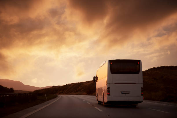 istock White bus driving on road towards the setting sun 905139190