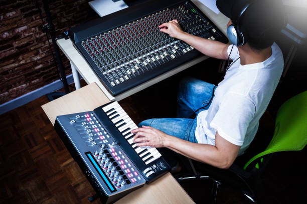istock male musician playing midi keyboard synthesizer in recording studio, focus on hands 905143780
