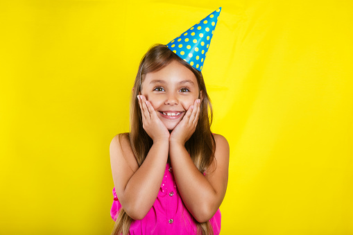 Studio portrait of a little girl wearing a party hat on her birthday. Cute girl Having fun.
