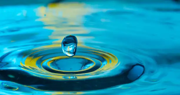 Photo of water drop in a glass of water