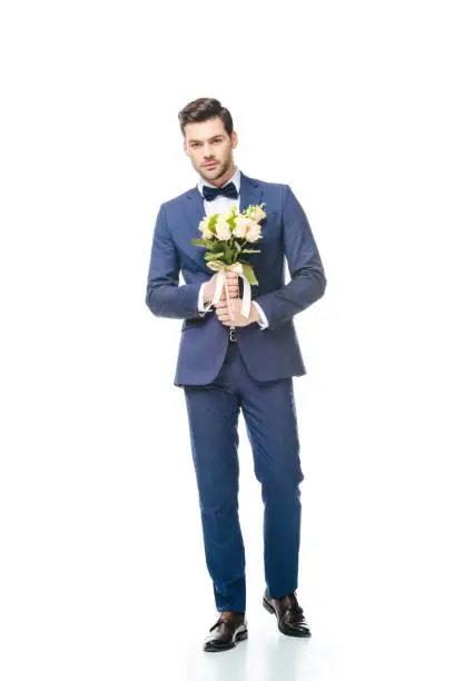 fashionable groom with wedding bouquet in hands isolated on white